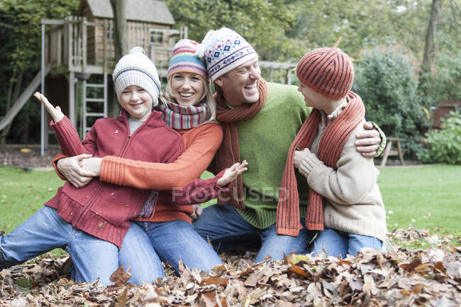 Portrait of family, sitting in autumn leaves — Stock Photo