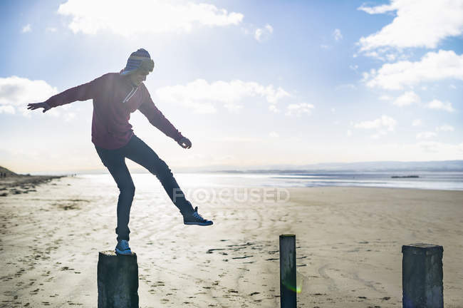 Young man standing on groynes, Brean Sands, Somerset, England — Stock Photo