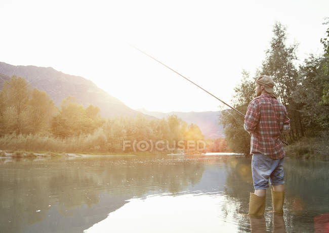 Rear view of young man fishing in lake, Premosello, Verbania, Piemonte, Italy — Stock Photo
