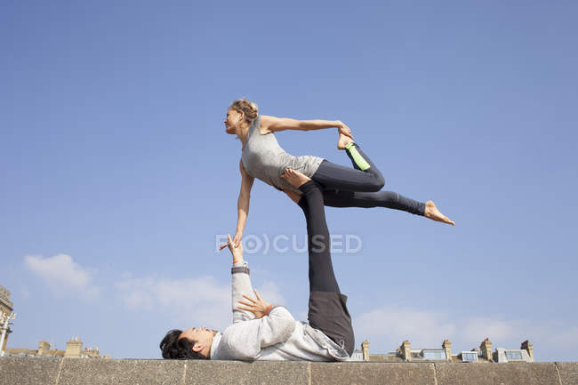 Мужчина и женщина практикуют акробатическую йогу на стене — стоковое фото