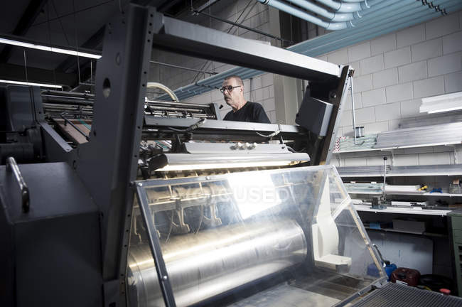 Arbeiter bedient Druckmaschine in Druckereiwerkstatt — Stockfoto