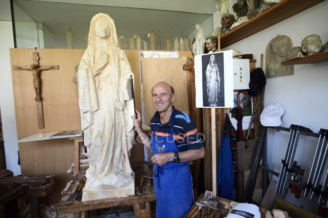 Sculpteur debout avec figurine en bois — Photo de stock