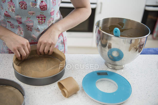 Female hands lining cake tins with greaseproof paper in bakery — Stock Photo