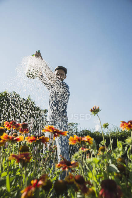 Giardiniere irrigazione fiori all'aperto — Foto stock