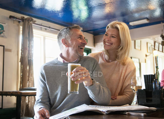 Paar lacht und liest Zeitung in Kneipe — Stockfoto