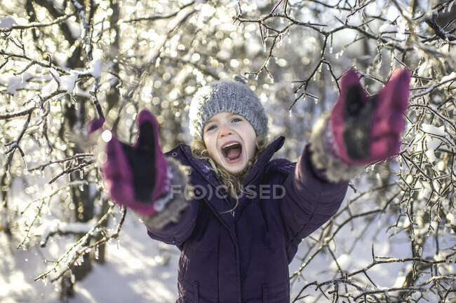 Young girl laughing, arms outstretched, in snowy landscape — Stock Photo