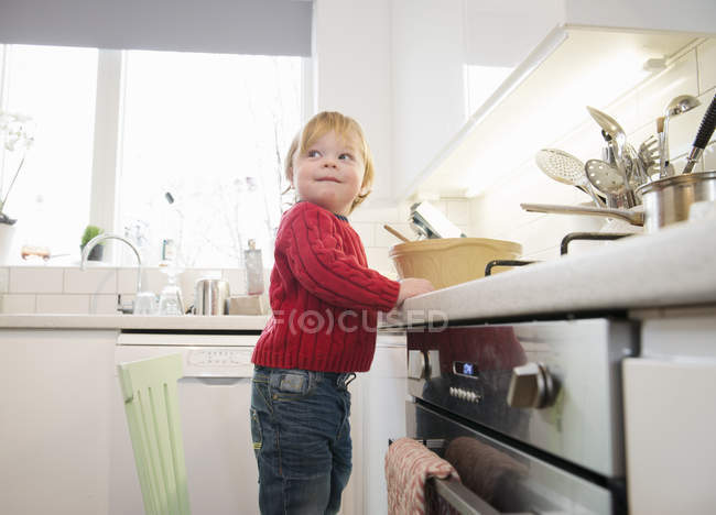 Boy standing on chair in kitchen — Stock Photo