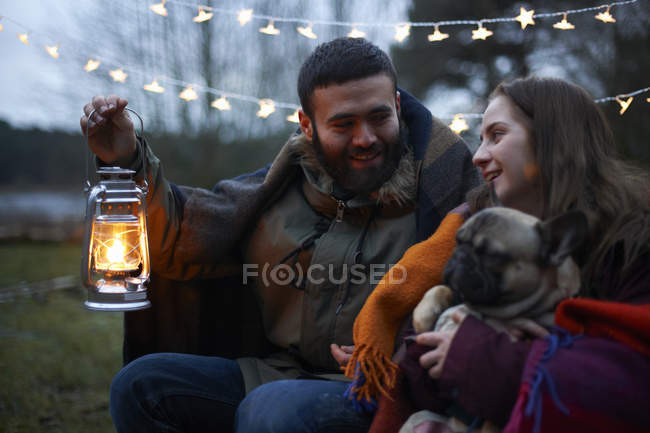Casal de acampamento jovem com cão envolto em cobertor — Fotografia de Stock