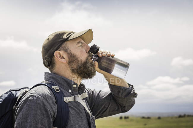 Hombre excursionista beber de botella de agua, Cody, Wyoming, EE.UU. - foto de stock