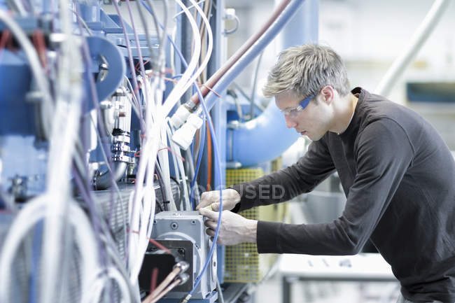 Середній дорослий чоловічий технік підтримує кабелі на інженерному заводі — стокове фото