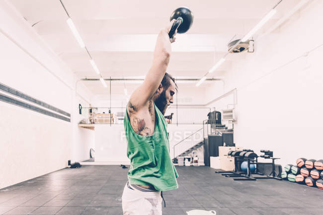 Junge männliche Crosstrainer Gewichtheben Kettlebell in der Turnhalle — Stockfoto