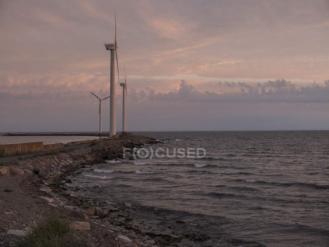 Прибрежные ветряные турбины с облачным небом на рассвете — стоковое фото