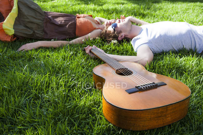 Romántica pareja joven tumbada en el jardín césped - foto de stock