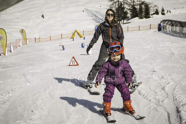 Madre e hija esquiando juntas, sonriendo - foto de stock