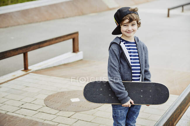 Мальчик-скейтборд смотрит в камеру улыбаясь — стоковое фото