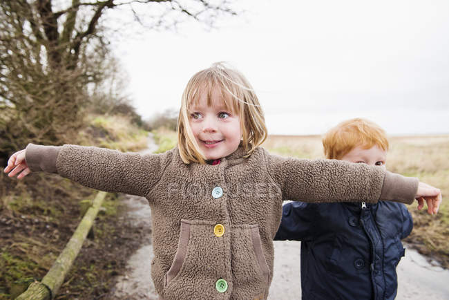 Little sister and brother playing on rural road — Stock Photo