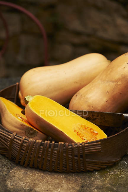 Halved and whole butternut squash in wicker basket — Stock Photo