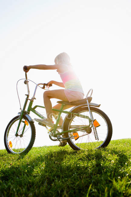 Дівчина їде на велосипеді в траві — стокове фото
