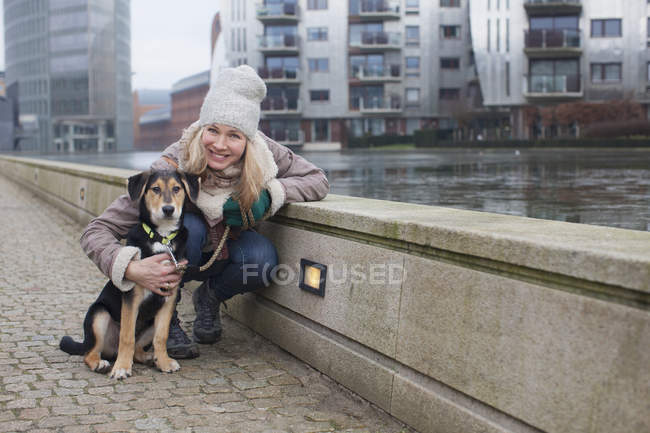 Porträt einer erwachsenen Frau und ihres Hundes am Ufer der Stadt — Stockfoto
