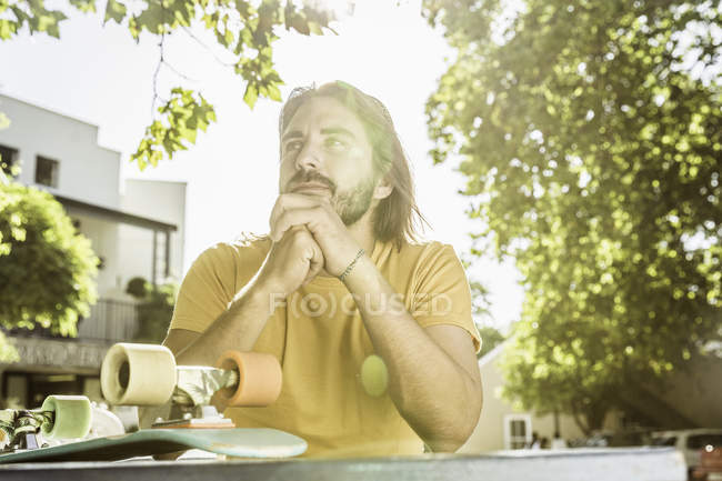 Young male skateboarder gazing from sidewalk cafe table, Franschhoek, South Africa — Stock Photo