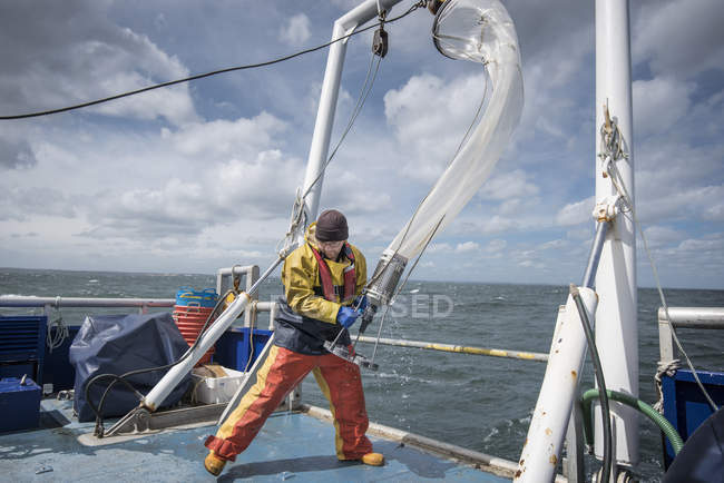 Un scientifique amène un filet de plancton à bord d'un navire de recherche — Photo de stock