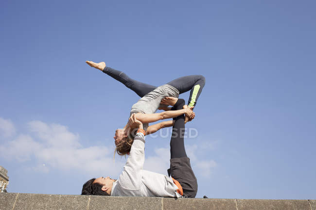 Мужчина и женщина на стене практикуют акробатическую йогу — стоковое фото