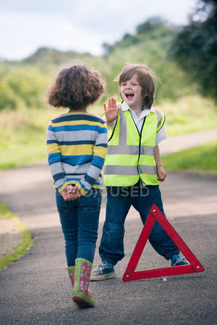 Boy playing traffic worker on rural road — Stock Photo