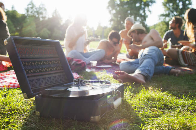 Adult friends relaxing and listening to record deck at sunset park party — Stock Photo