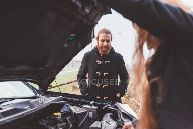 Casal olhando para o motor do carro na estrada — Fotografia de Stock