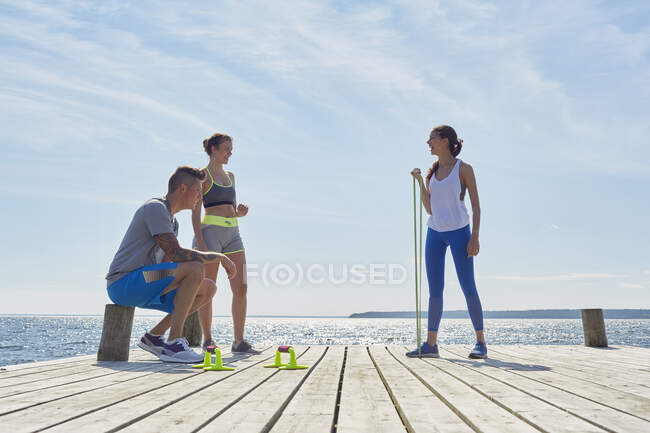 Friends wearing sports clothes on pier with exercise equipment — Stock Photo