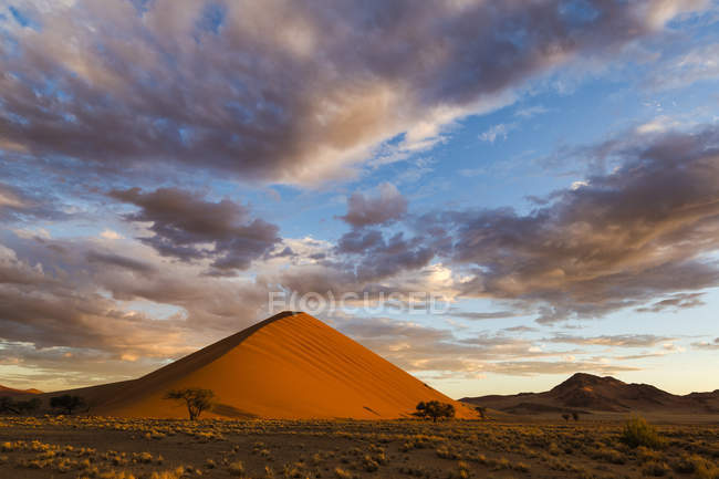 Lever de soleil sur une dune de sable avec nuages au-dessus, Soussvlei, Namibie — Photo de stock