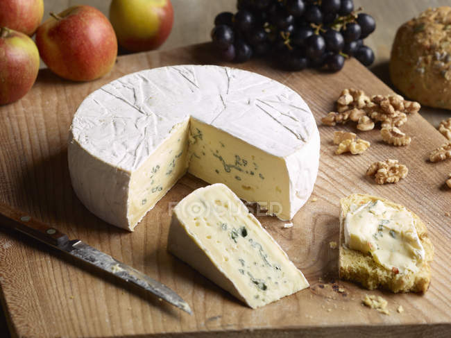Stillleben von blauem Brie mit Walnüssen, Trauben und Äpfeln auf Schneidebrett — Stockfoto