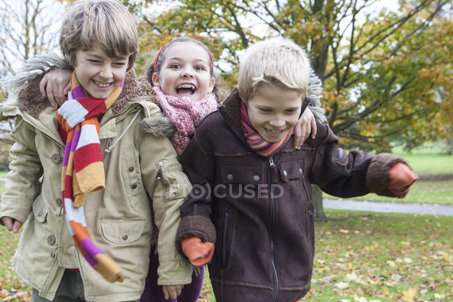 Tres niños corriendo en el parque, riendo - foto de stock