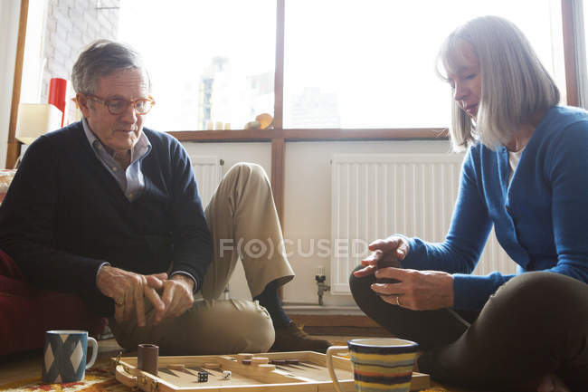 Couple playing backgammon on floor — Stock Photo