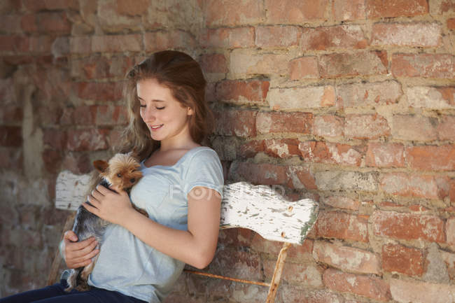 Дівчина-підліток сидить на лавці з собакою — стокове фото