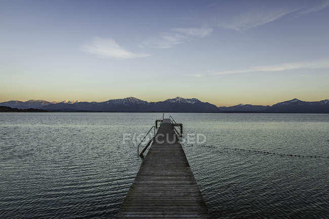Wooden pier with view of mountains at dusk — Stock Photo