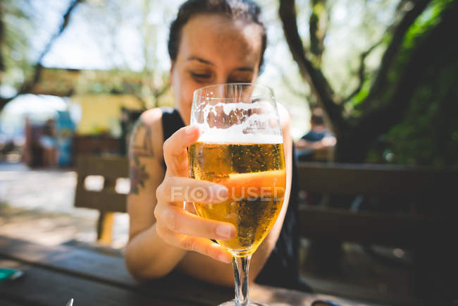 Woman holding up glass of beer, Garda, Italy — Stock Photo