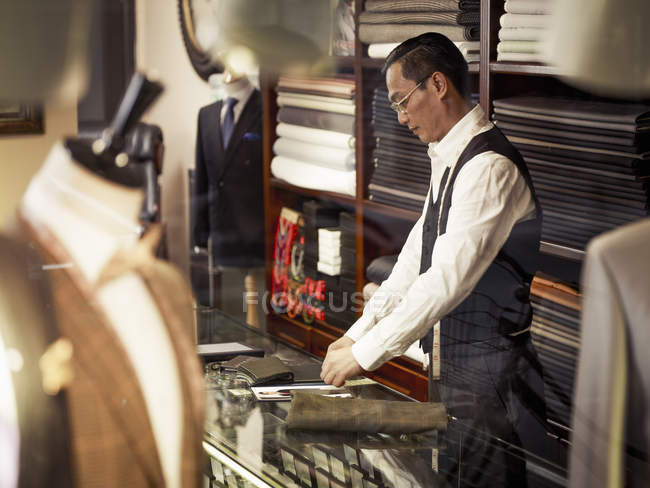 Tailleur travaillant au comptoir dans le magasin de tailleurs — Photo de stock