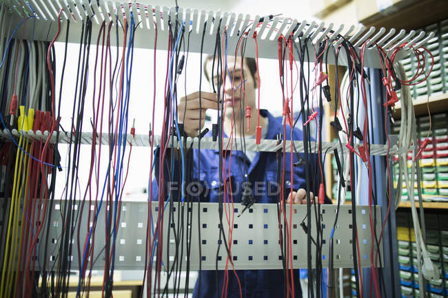 Électricien masculin sélectionnant le câble d'alimentation en atelier — Photo de stock
