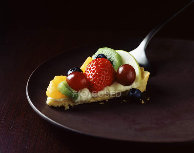 Scheibe Erdbeere, Kiwi, Orange und Traubenkuchen auf Teller — Stockfoto