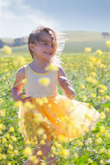 Chica sonriente jugando en el campo de las flores - foto de stock