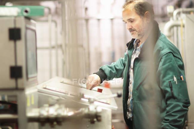 Travailleur de brasserie faisant fonctionner la machine en usine — Photo de stock