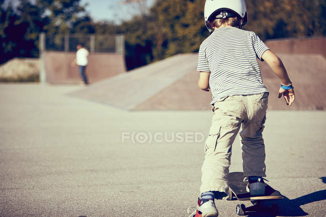 Petit garçon en casque skateboard dans le parc — Photo de stock