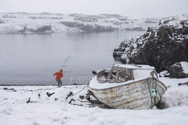 Mann wirft im Winter Stein ins Seewasser — Stockfoto