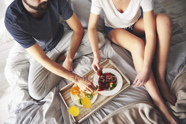 Erhöhter Blick auf ein junges Paar beim Frühstück im Bett — Stockfoto