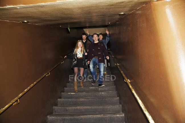 Group of friends coming down stairs into nightclub — Stock Photo