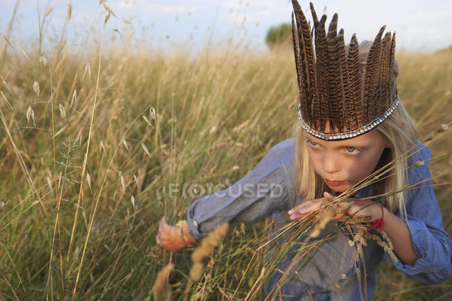 Девушка прячется в длинной траве, одетая как коренной американец — стоковое фото