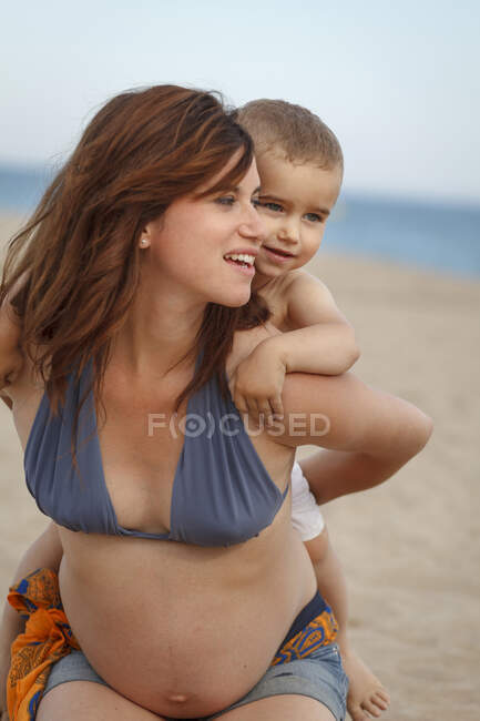 Pregnant mother giving toddler piggy back — Stock Photo