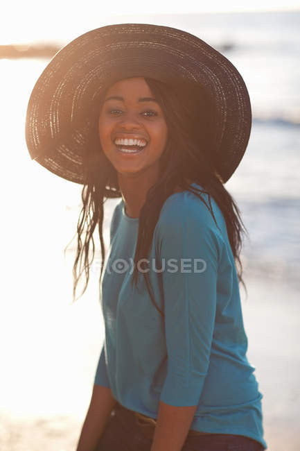 Lächelnde Frau mit Sonnenhut am Strand — Stockfoto