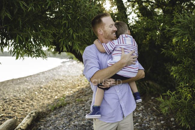 Padre e hijo pequeño abrazándose en el Lago Ontario, Oshawa, Canadá - foto de stock